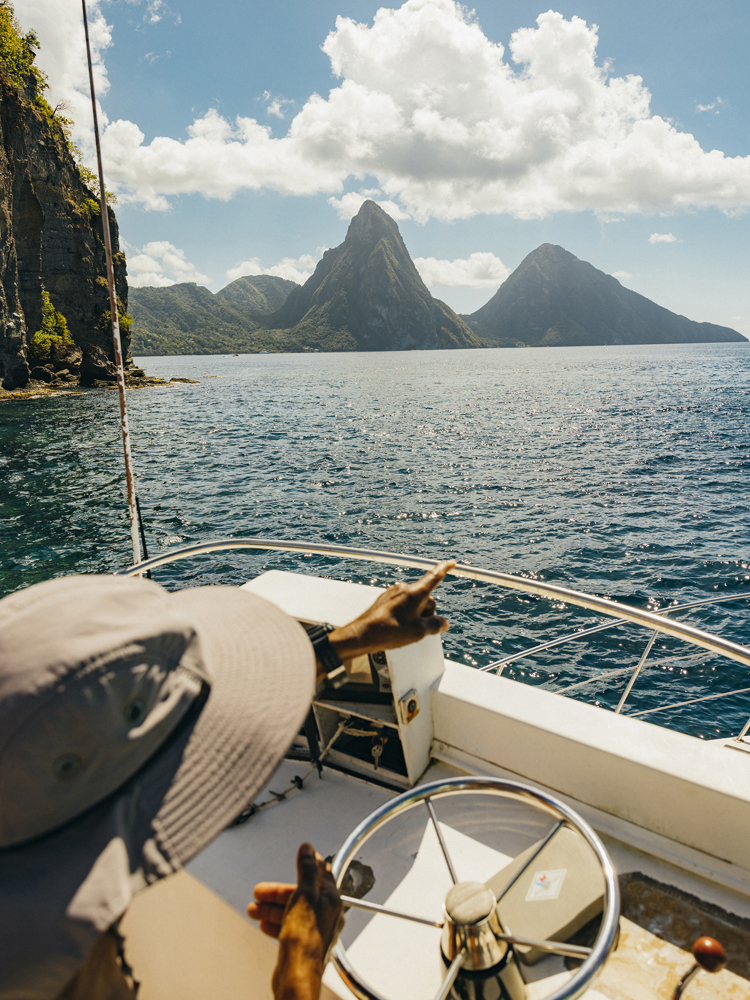 A man in a boat pointing to mountains in St Lucia.