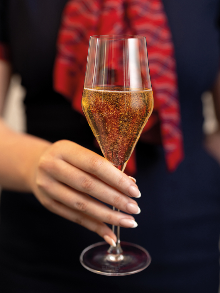 A British Airways colleague holding a glass of sparkling wine.