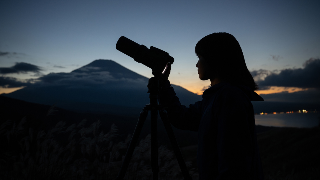A woman using the Nikon Coolpix P1100 at night.