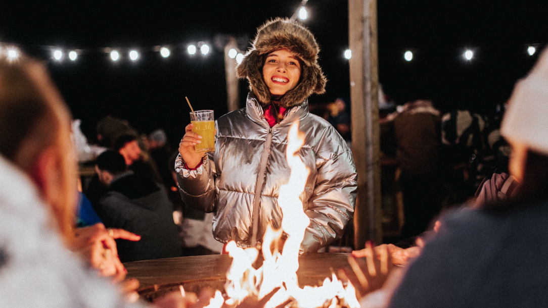A woman enjoying an open fire at La Folie Douce Hotels Chamonix.