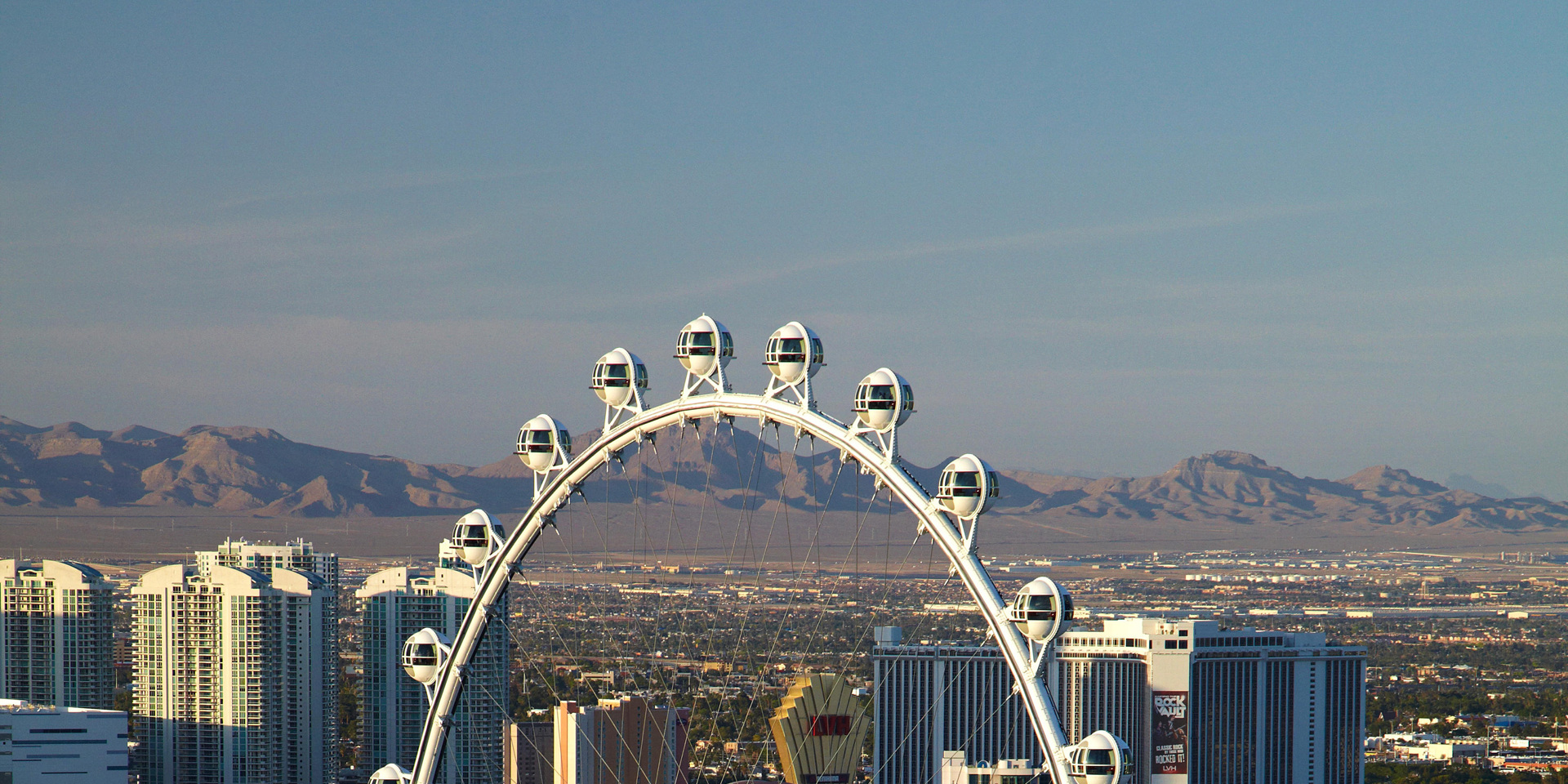 A ferris wheel in Las Vegas with a view of mountains in the distance.