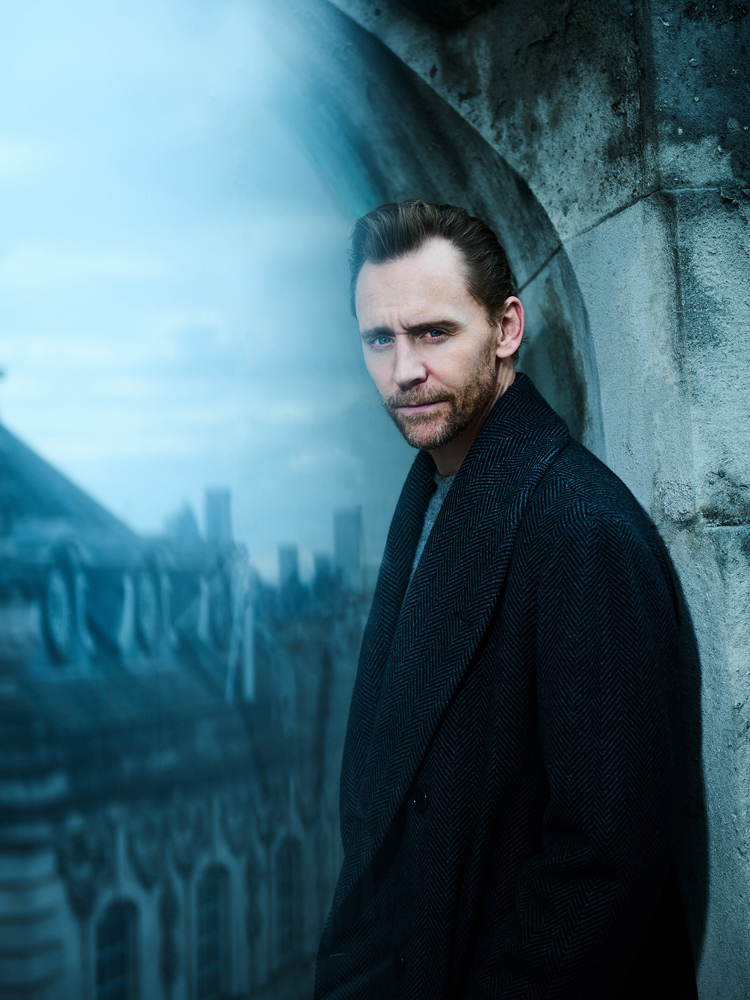 Tom Hiddleston against a window with the silhouette of a building.