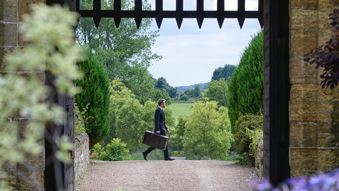 A member of staff at Amberley Castle seen through an arch with a portcullis at the top.