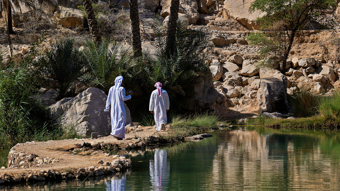 Two men walking along Wadi Bani Khalid